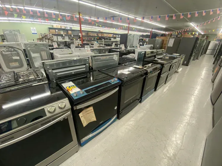 Rows of new kitchen appliances displayed in a brightly lit store with American flags.