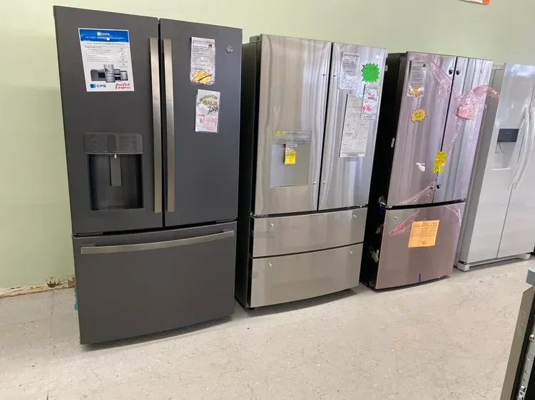 Several refrigerators of different colors are lined up in a store.