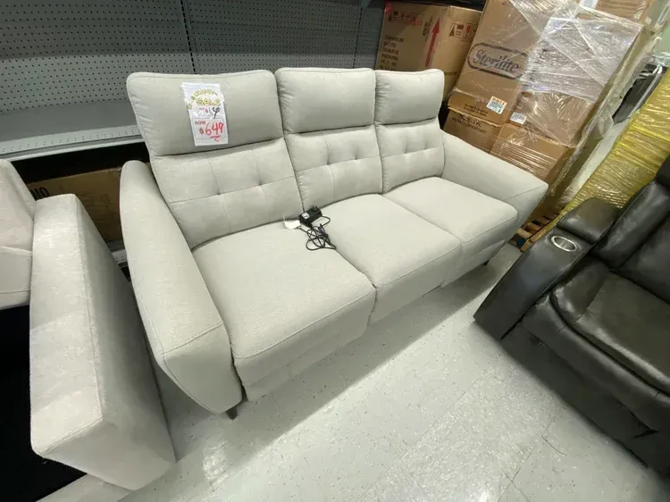 Light gray reclining sofa with three seats, in a store setting.