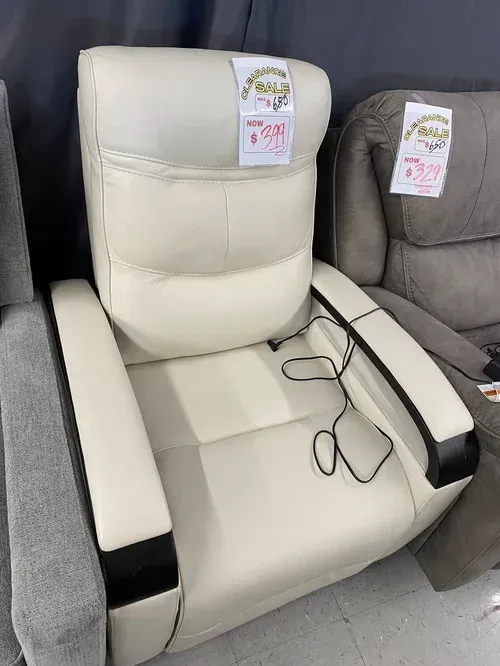 Cream-colored, leather recliner with black accents and attached cord. Tag reads 