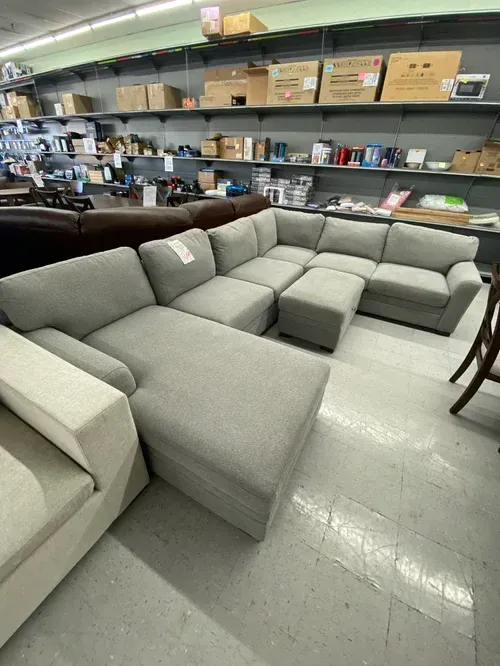 Gray sectional sofa with a chaise in a warehouse setting.