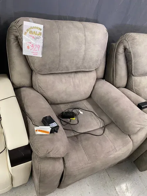 A light gray recliner chair with a control unit, for sale in a store.