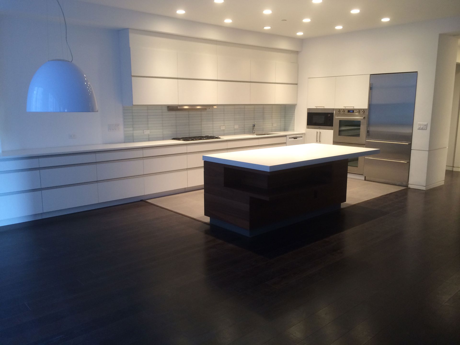 Modern white kitchen with dark floors, island, and stainless steel appliances