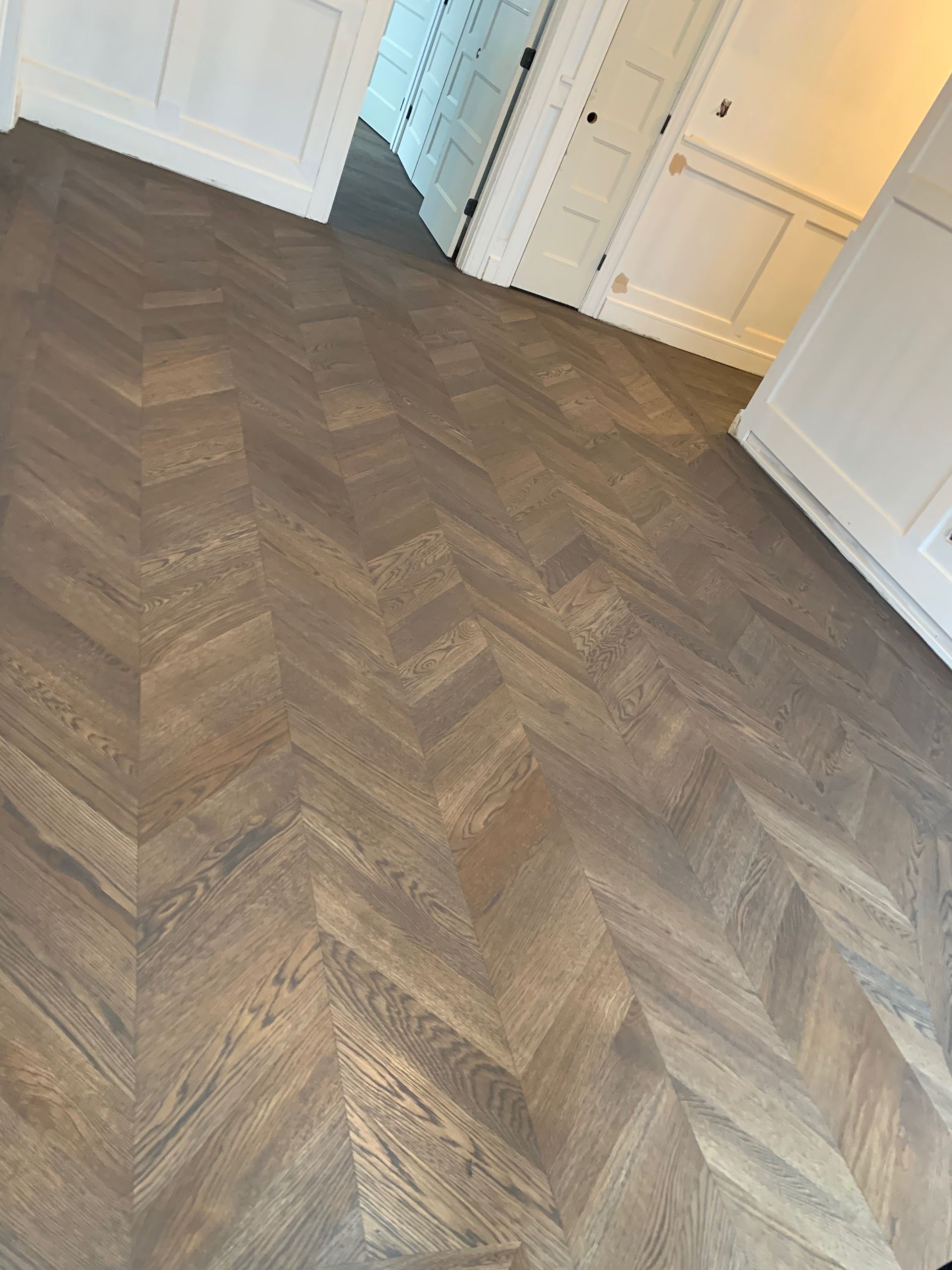 Empty room with herringbone wood floor and white doors along the walls