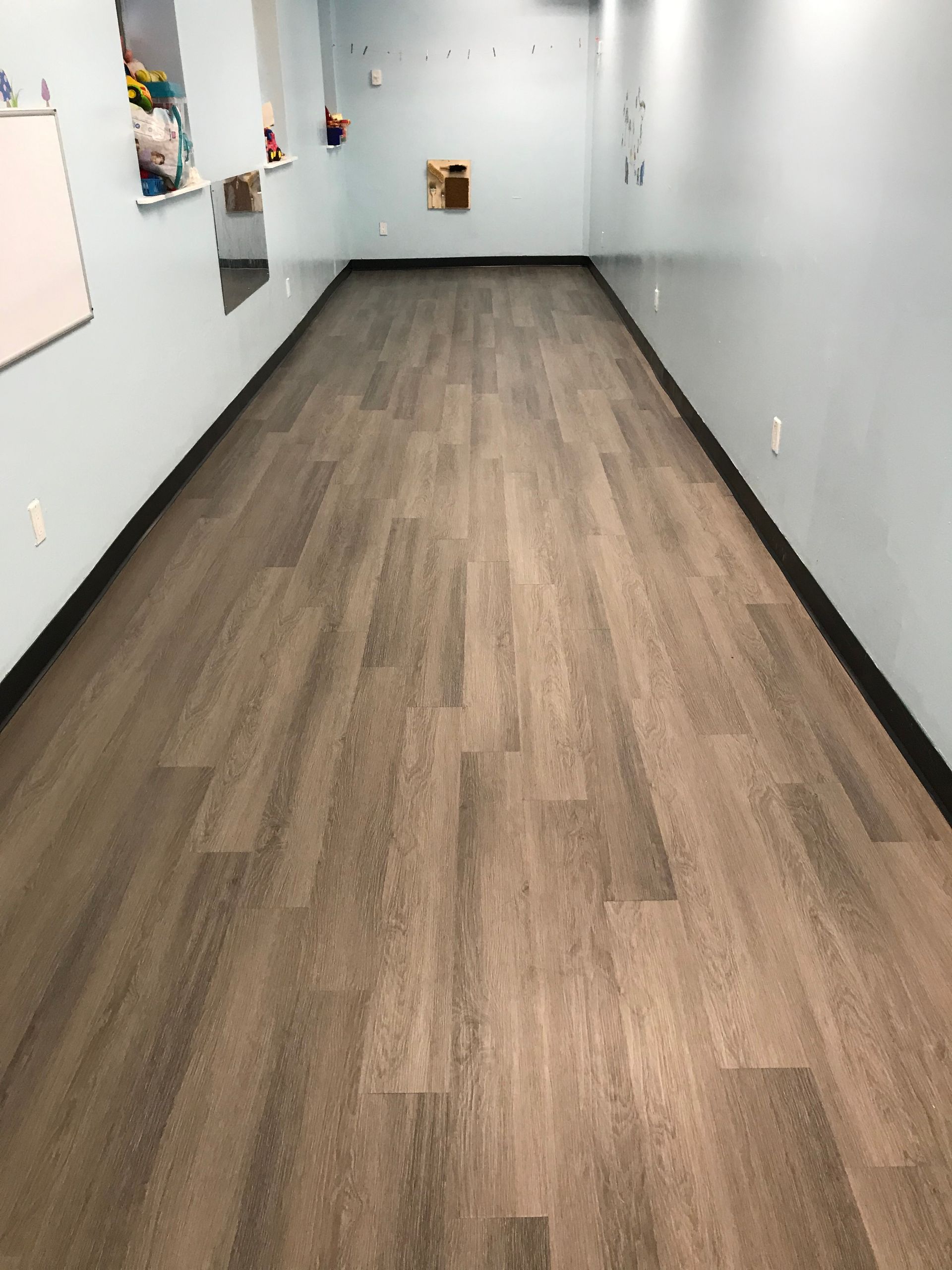 Empty hallway with wood-patterned floor and light gray walls