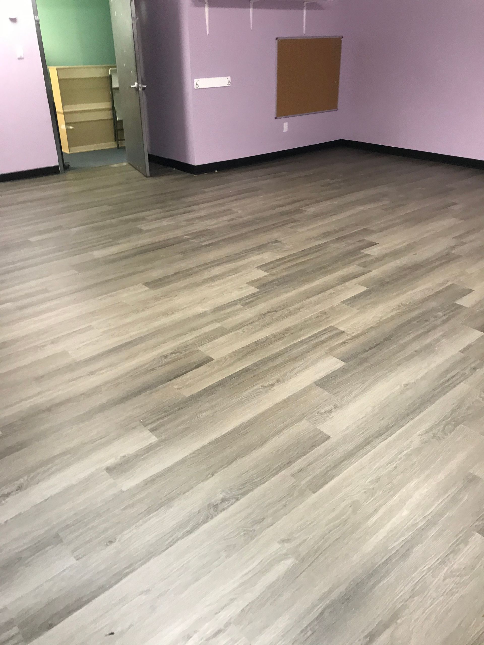 Empty room with wood flooring, purple walls, and an open doorway.