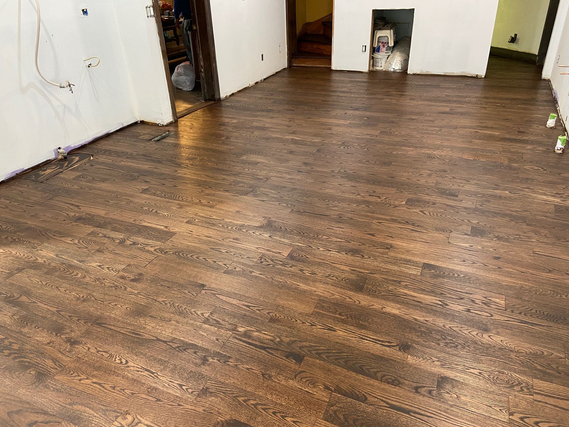 Empty room with dark wood flooring and white walls, viewed from a low angle.