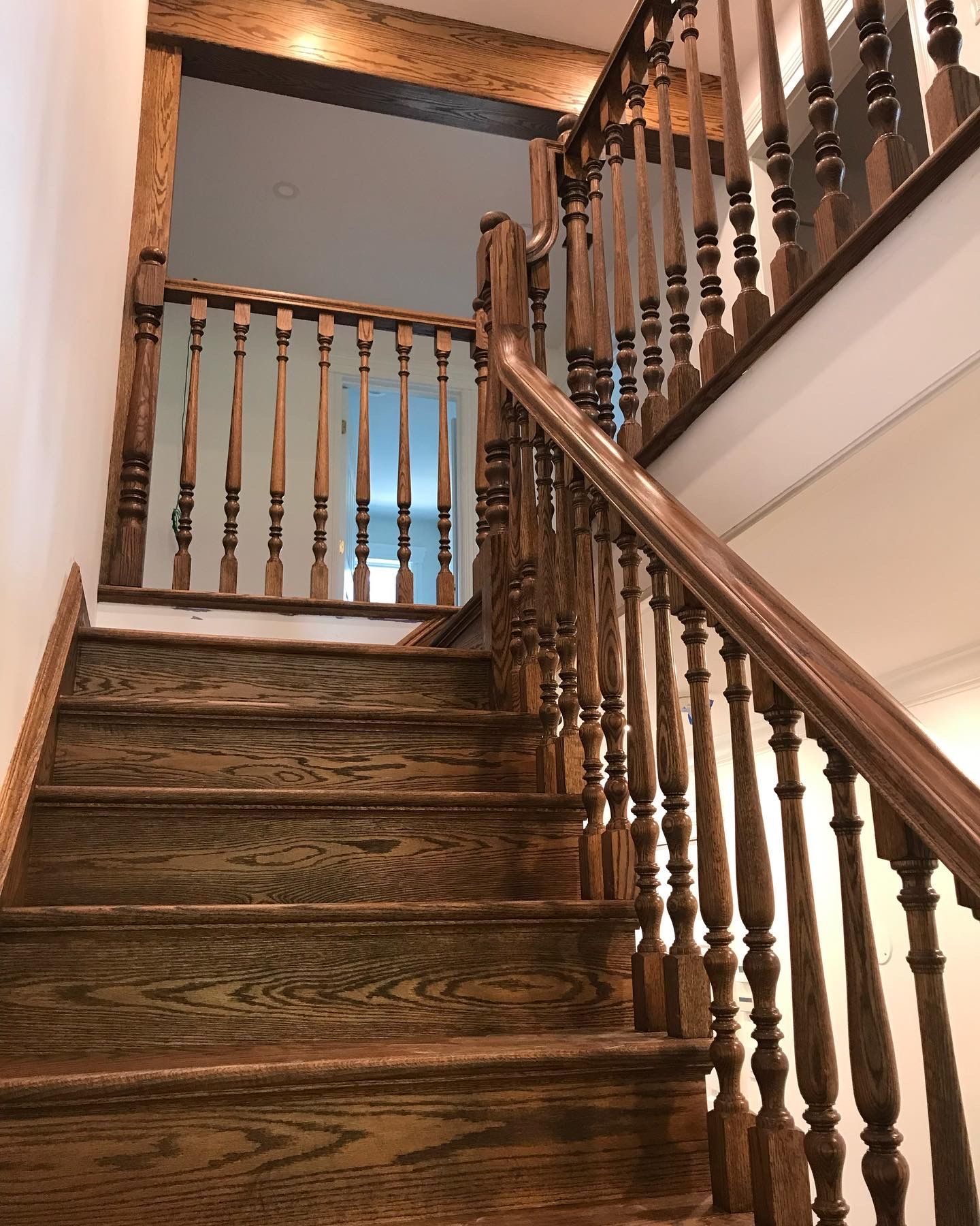 Wooden staircase with turned banisters in a warmly lit home interior