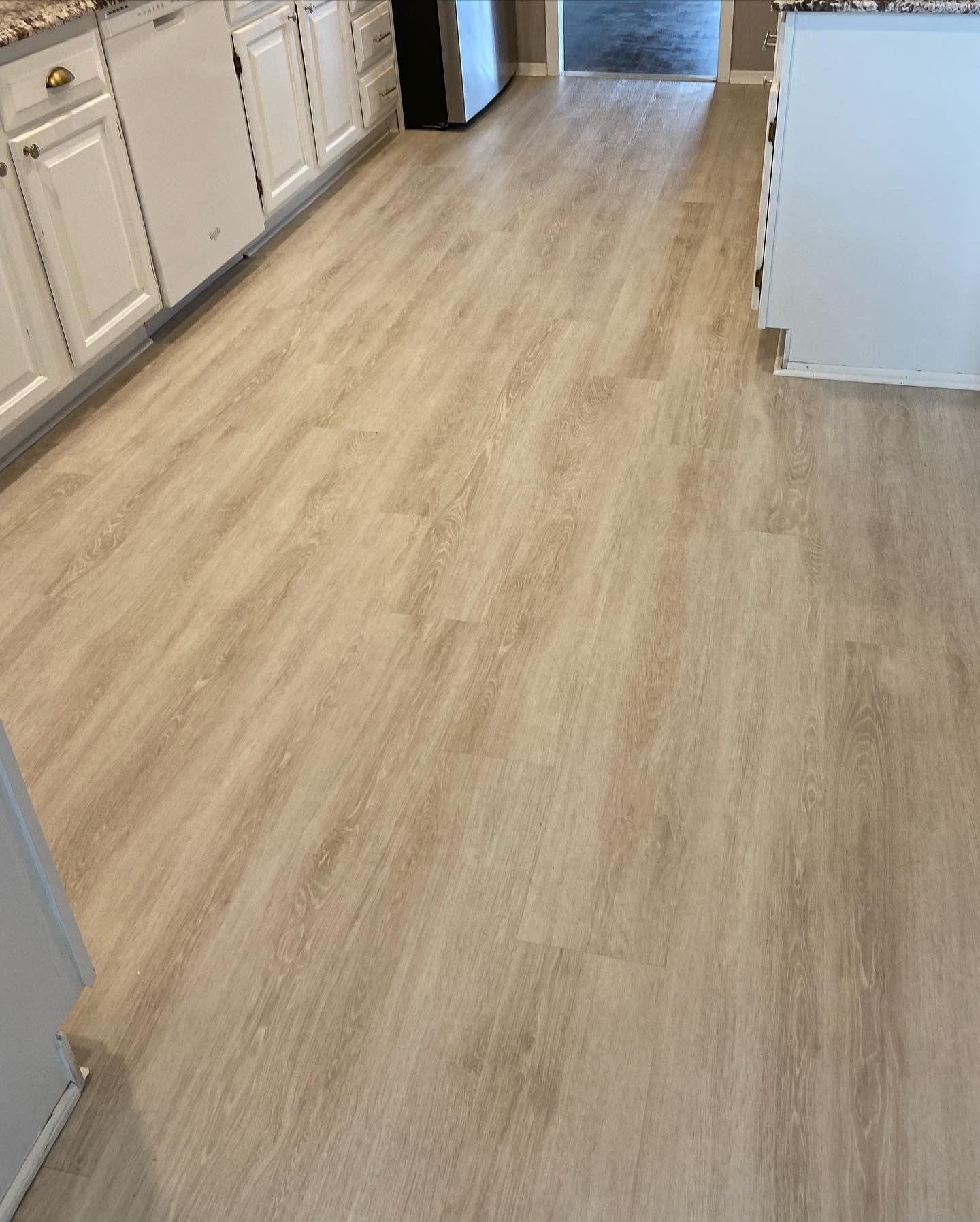 Kitchen with light wood flooring and white cabinets along the left side.