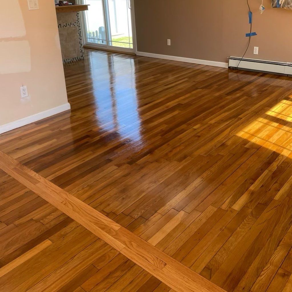 Empty room with glossy wood floors and sunlight reflecting from a sliding glass door