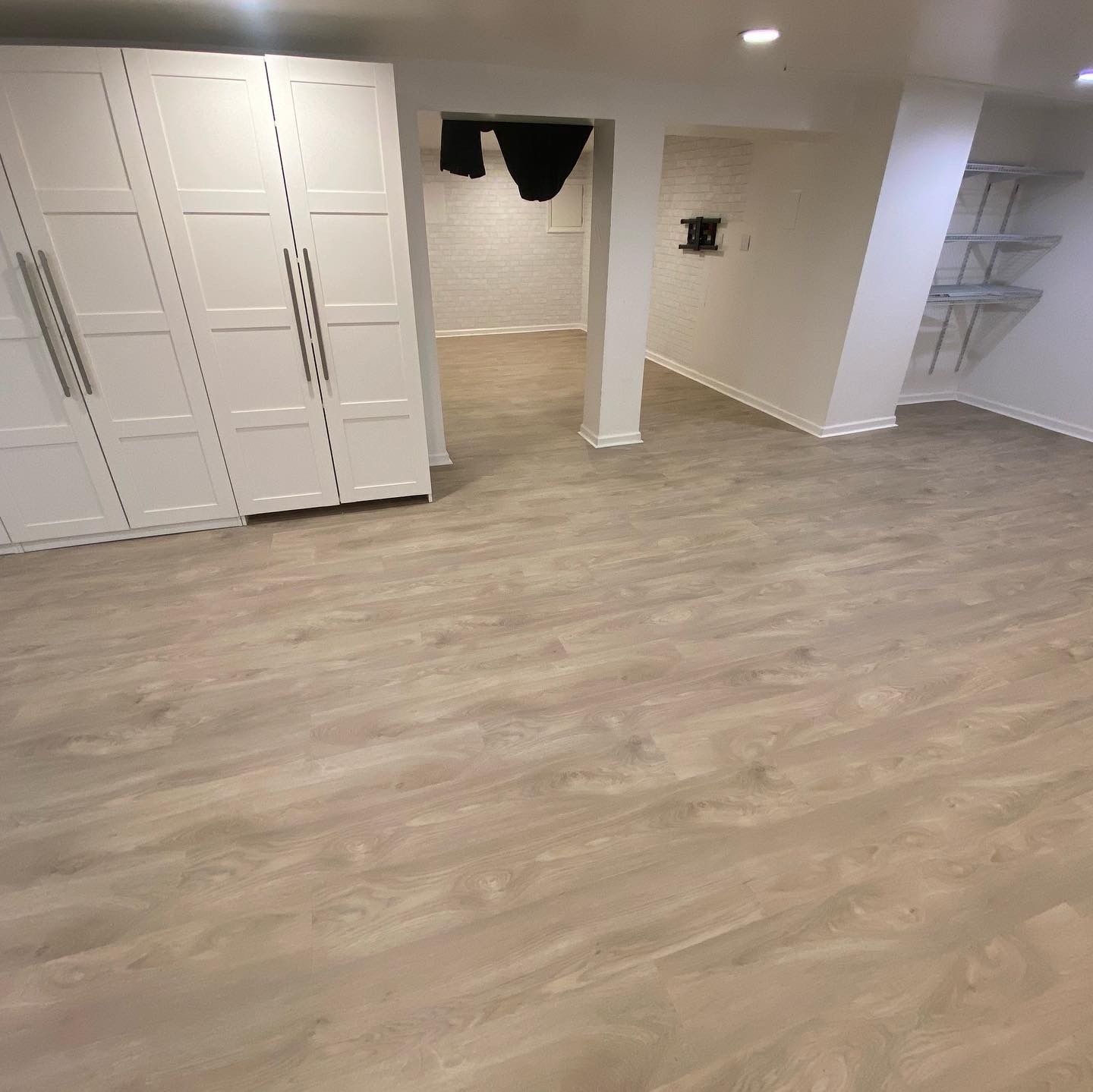 Empty carpeted room with white built-in closets, open alcove, and shelving on the right.