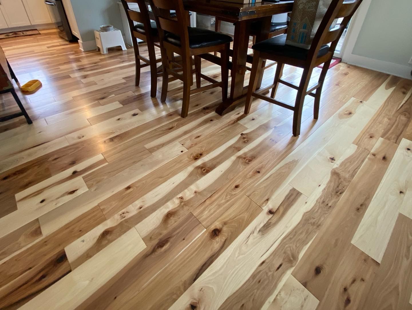 Light wood plank floor with a dark wooden dining table and chairs in a bright room