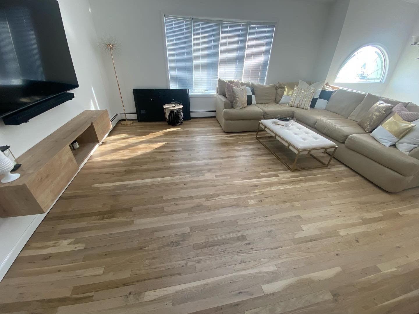 Bright living room with beige sectional sofa, fireplace, TV, and large windows letting in sunlight