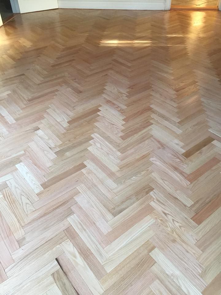 Sunlit herringbone wood floor in a bright empty room