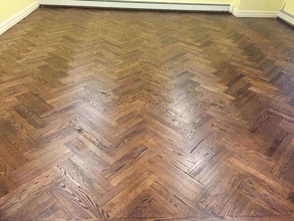 Empty room with glossy herringbone wood floor and pale yellow walls