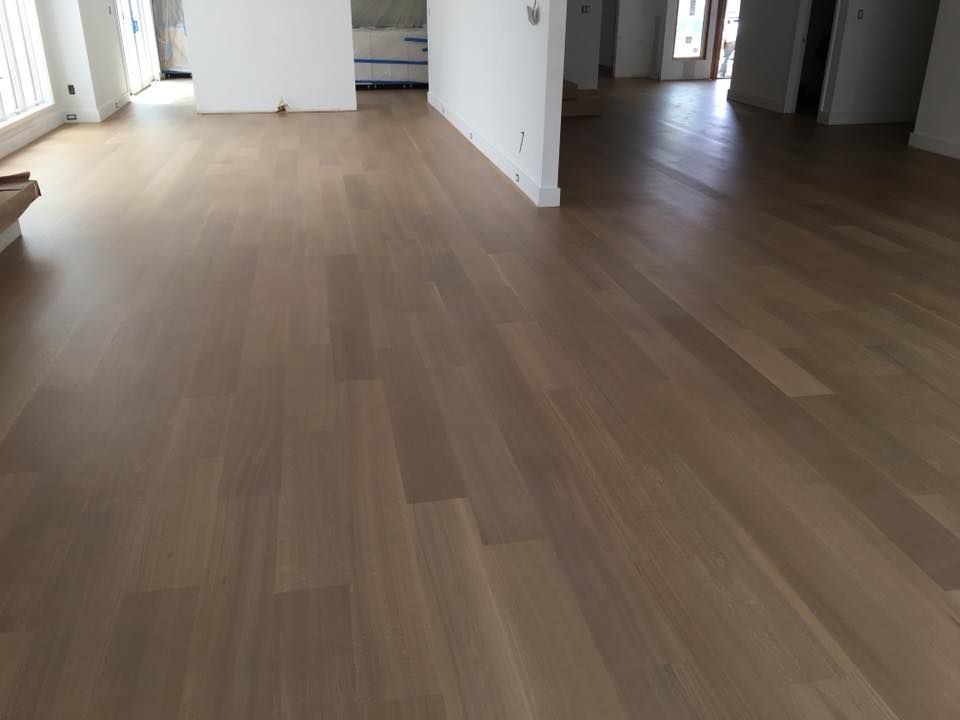 Empty modern room with light wood flooring and white walls, viewed from an open doorway.