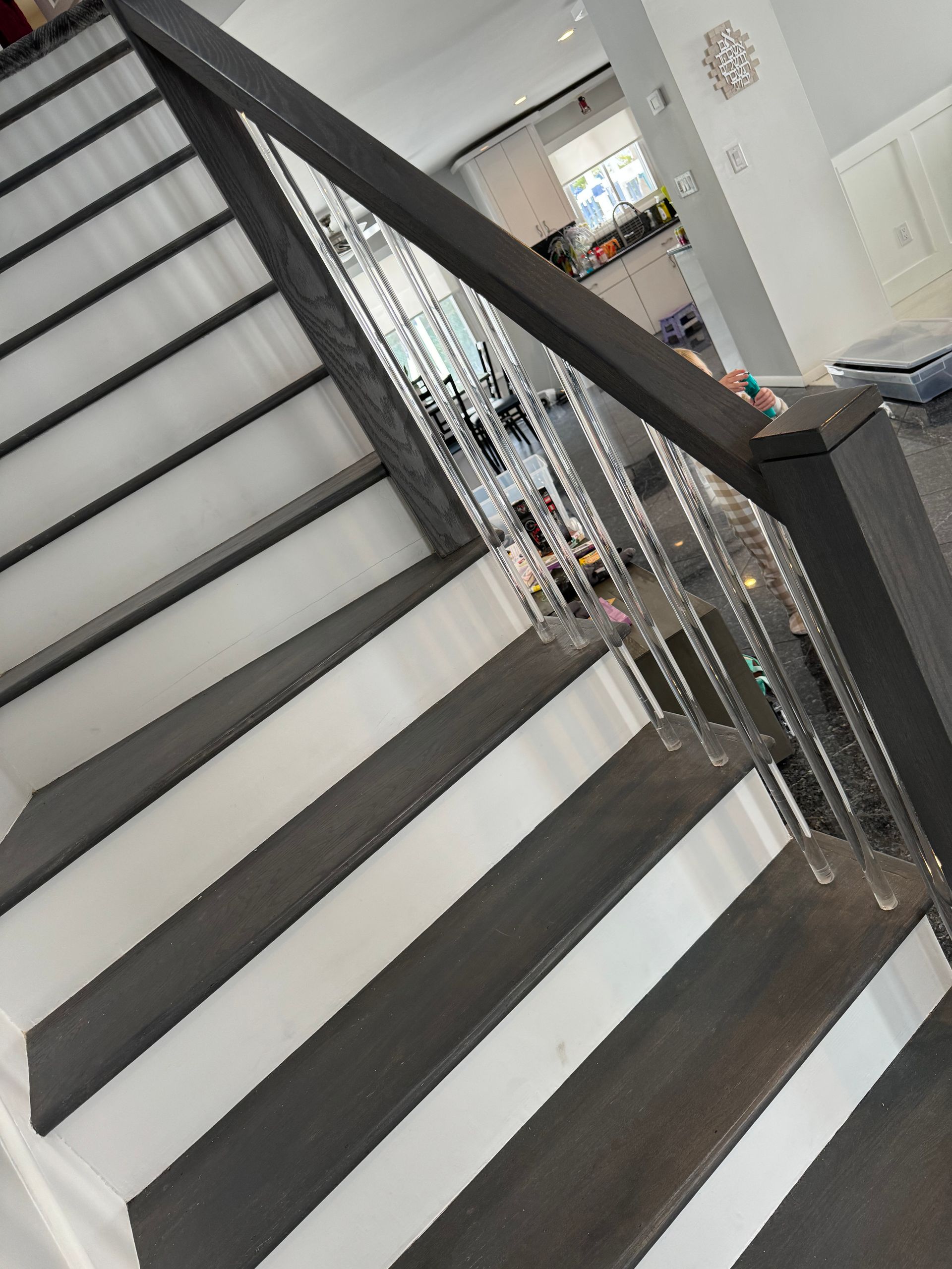 Indoor staircase with dark railing and white steps, viewed from the landing