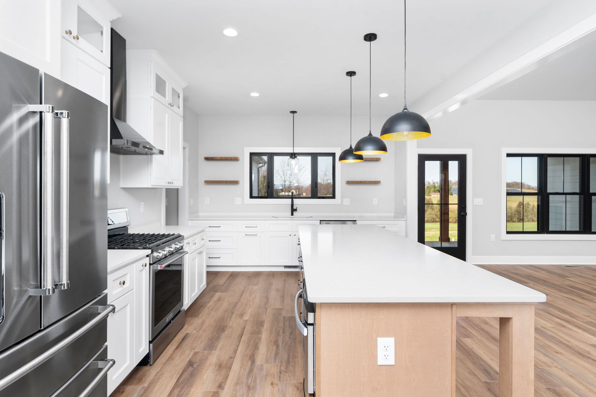 Modern kitchen with white cabinets, stainless steel appliances, and a large island with three pendant lights.