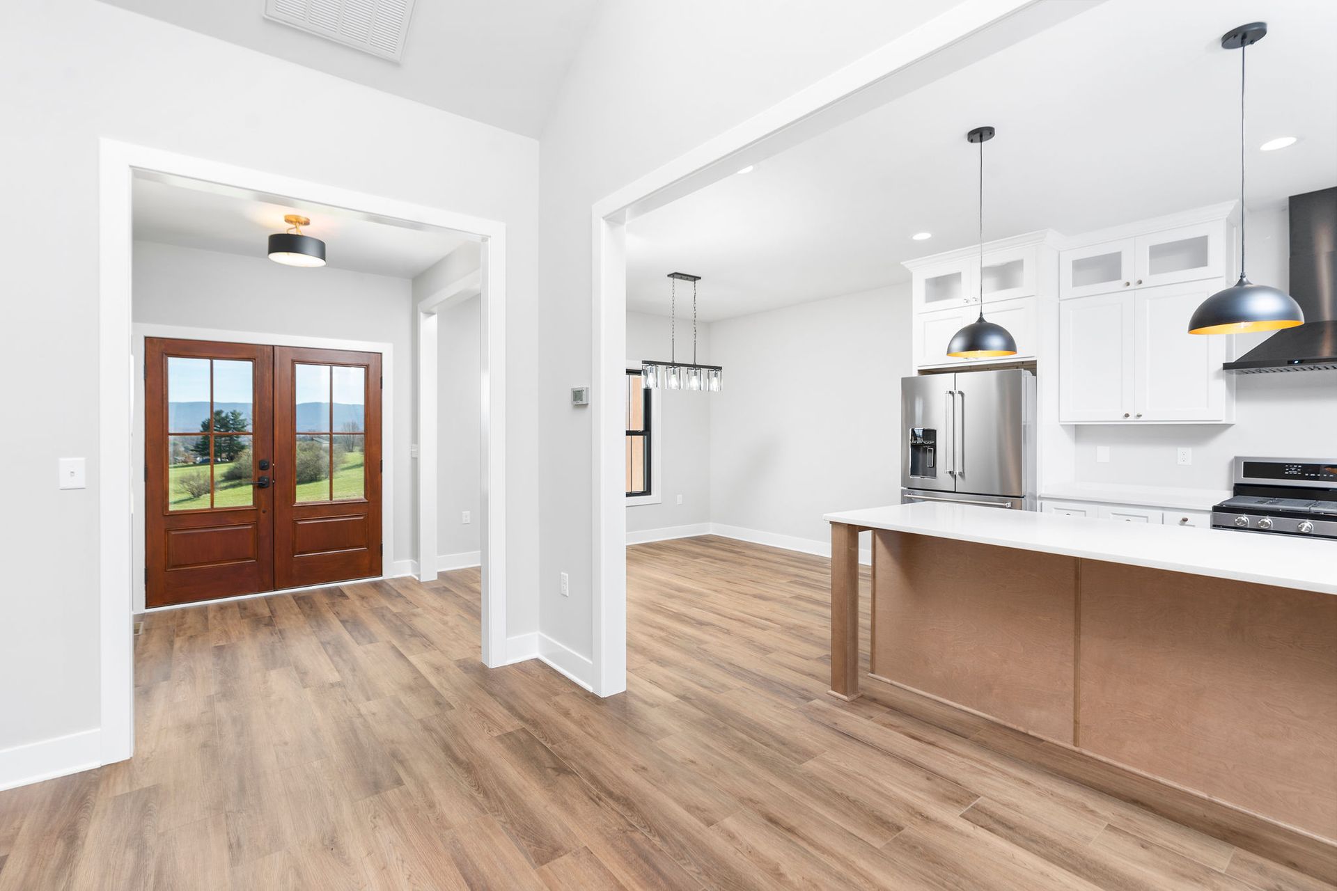 Open-concept home interior with wood floors, kitchen, and entry doors leading outside.