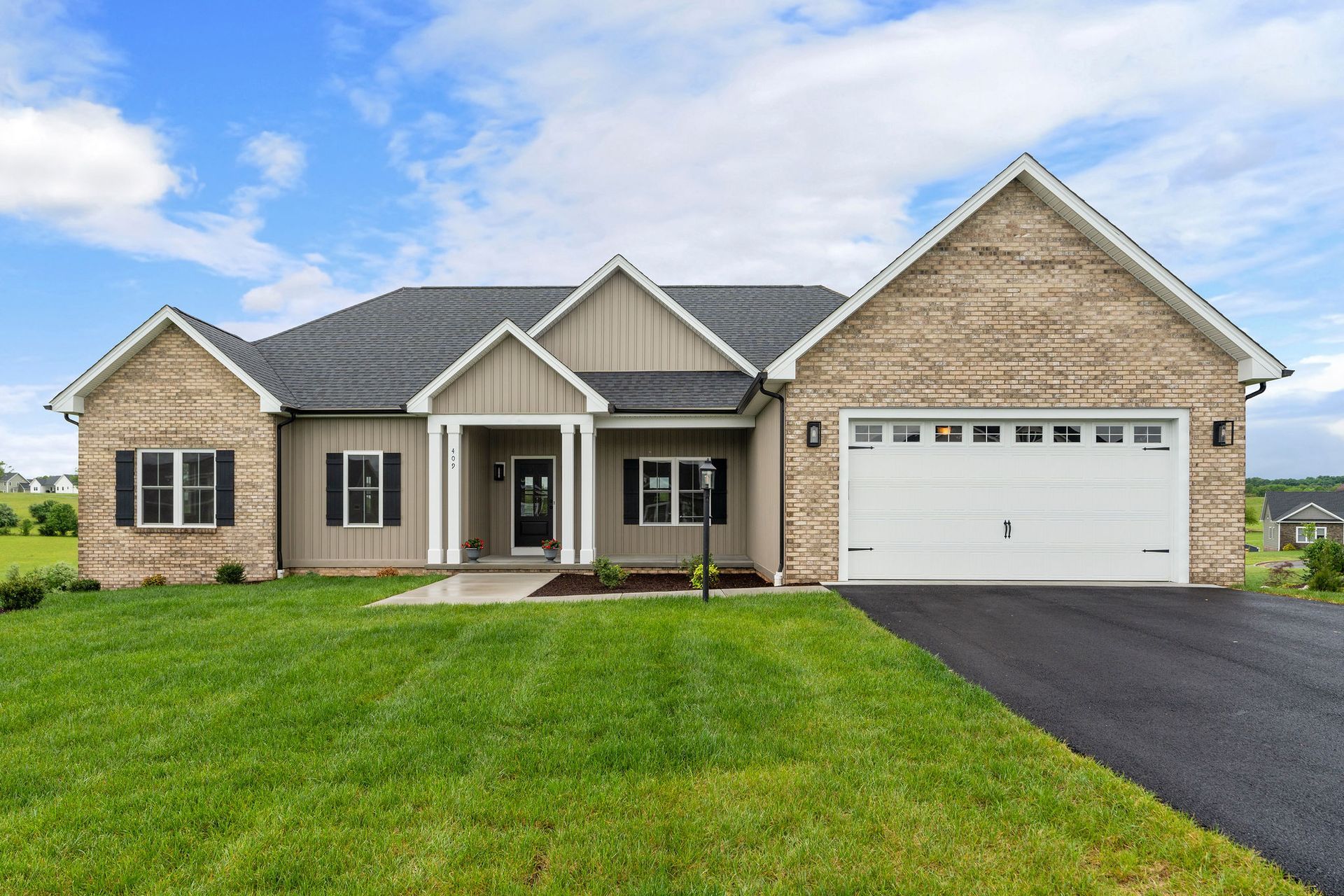 Tan brick and siding ranch-style house with a two-car garage under a blue sky.