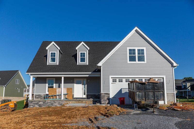 New gray house with a garage and dormers, under construction, blue sky.