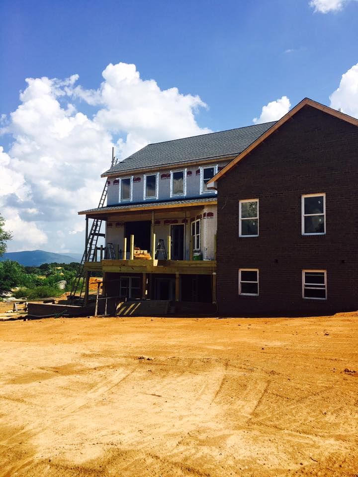 Building under construction with brown brick and wood framing against a cloudy sky.