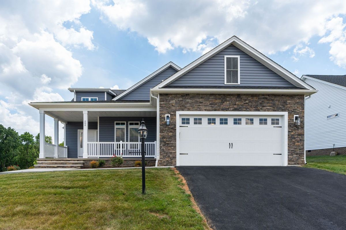 A modern house with a stone facade, gray siding, and a white garage door; a sunny day.