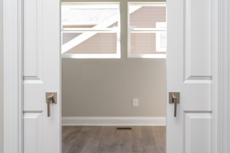 White double doors open to a room with windows and a neutral-colored wall.