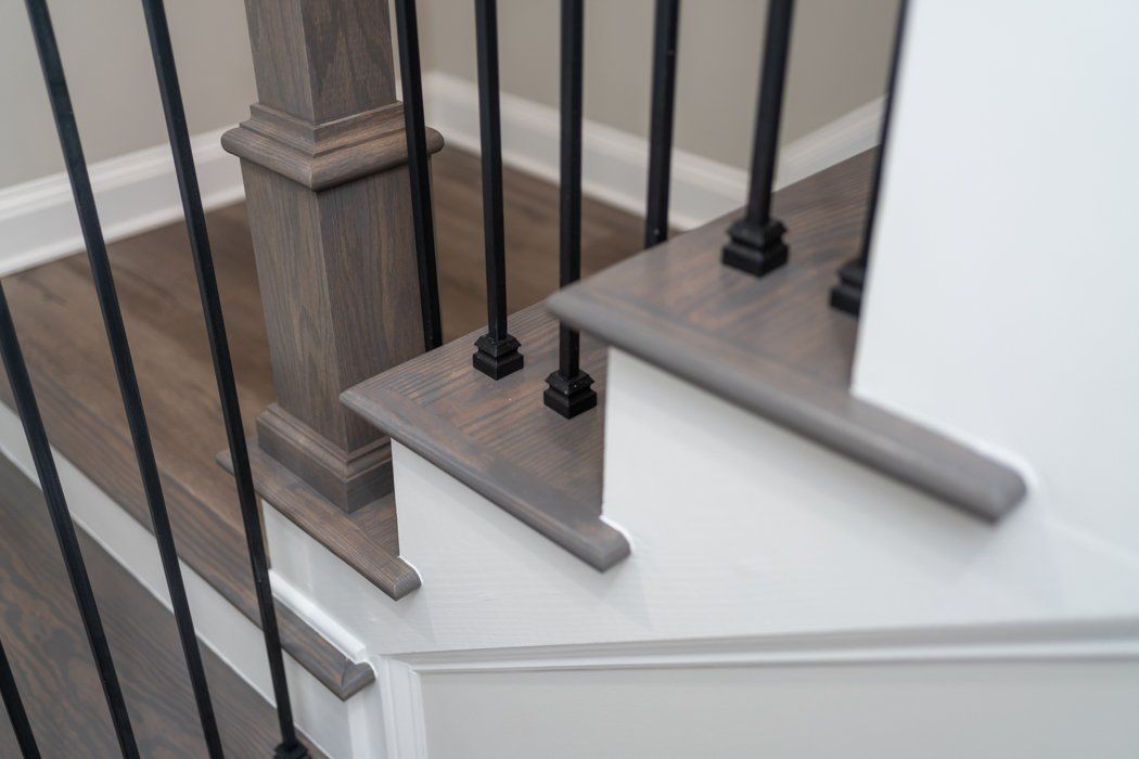 Wooden staircase with gray treads, white risers, and black metal railings.