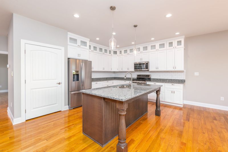 Bright kitchen with white cabinets, granite countertops, and a dark wood island.