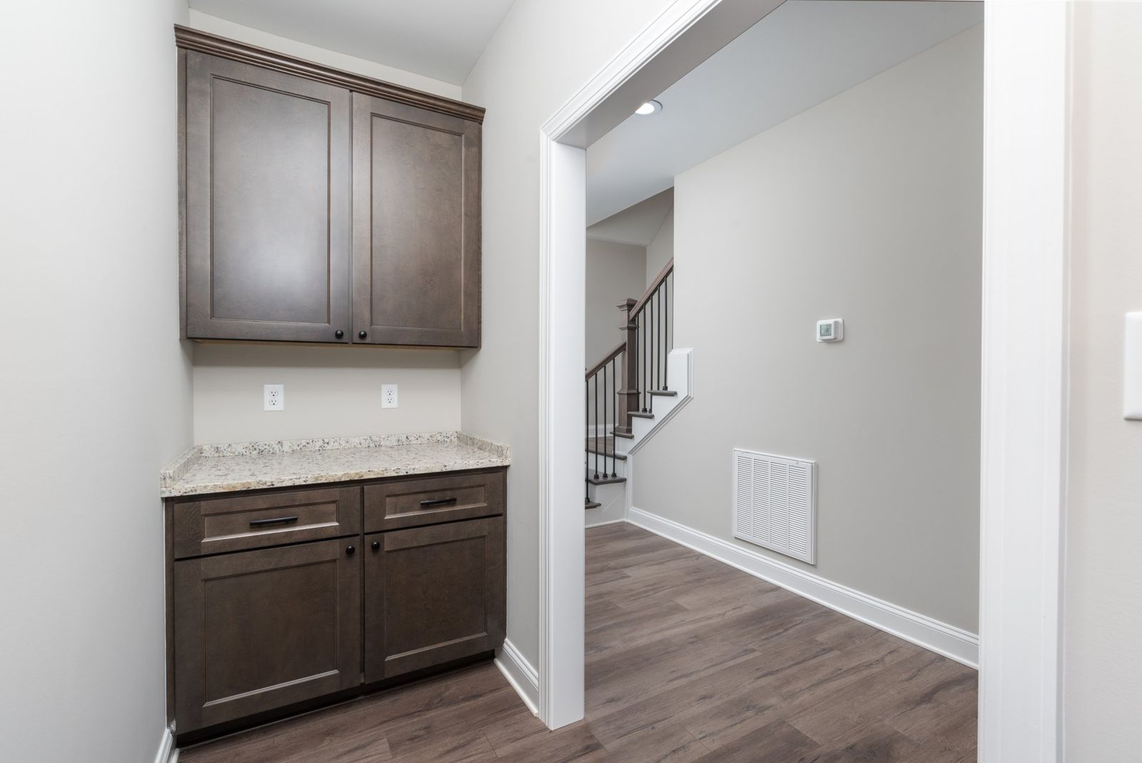 A narrow hallway with dark brown cabinets and a doorway to a staircase.