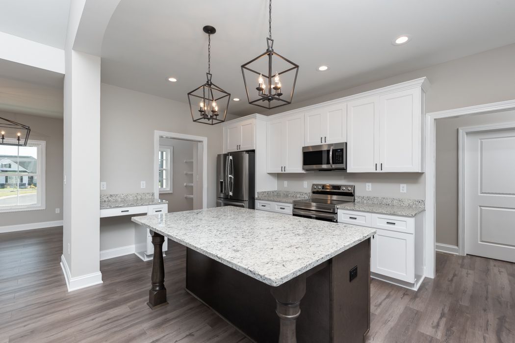 Modern kitchen with white cabinets, dark island, and granite countertops.