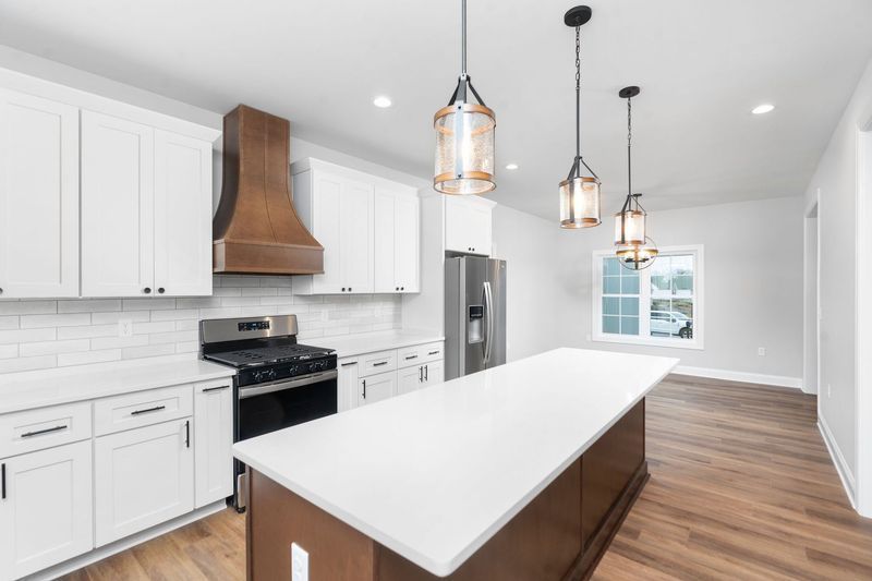 Modern kitchen with white cabinets, island, stainless steel appliances, and wooden accents.