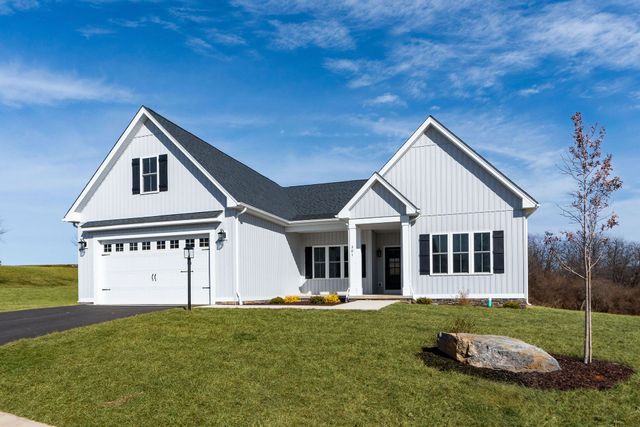 White house with dark gray roof, two-car garage, and black shutters, on a grassy hill.