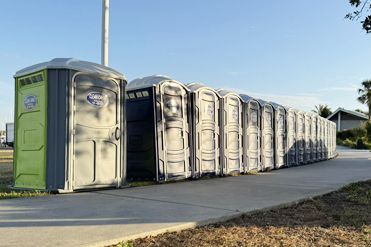 A row of portable toilets are lined up on a sidewalk.