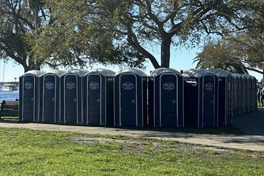 A row of portable toilets are lined up in a park.