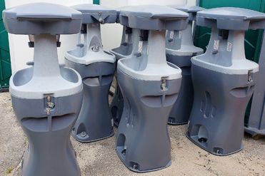 A row of gray toilets sitting next to each other on the ground.