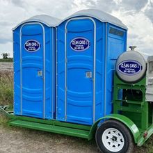 Two blue portable toilets are on a green trailer.