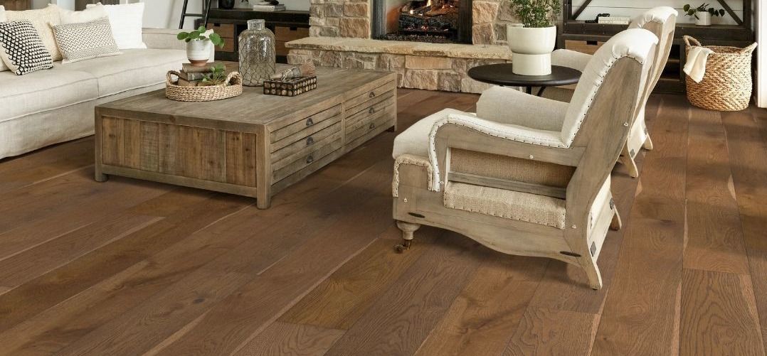 A living room with hardwood floors , a couch , chair , coffee table and fireplace.