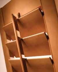Wooden shelf unit built into a wall, featuring several angled shelves. The shelves are a light brown color.