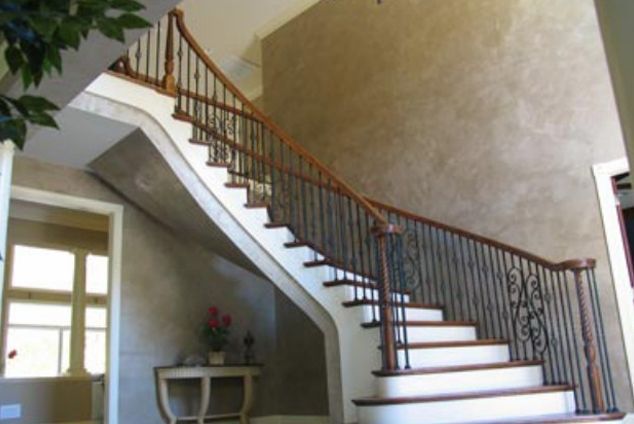 A curved staircase with a wrought iron railing