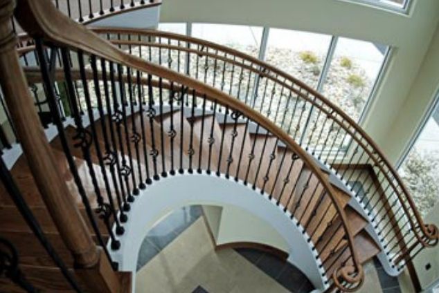 A curved staircase with a wrought iron railing