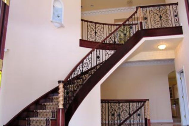 A wooden staircase with a wrought iron railing