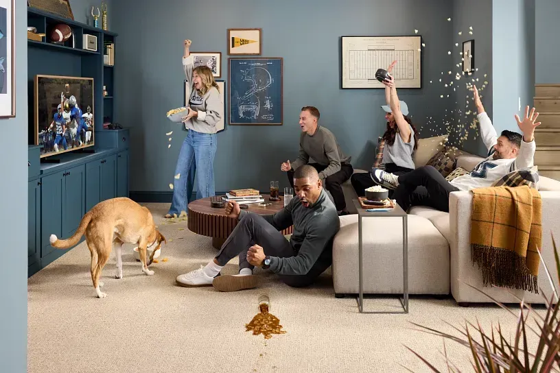 A group of people are sitting on a couch in a living room with a dog.