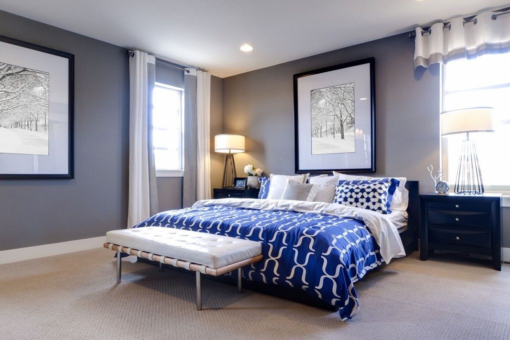Bedroom with a blue and white patterned bedspread, gray walls, and black furniture. Two framed prints hang on the walls.