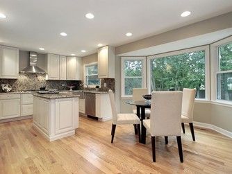 Kitchen with white cabinets, stainless steel appliances, and breakfast nook with table and chairs. Hardwood floors.