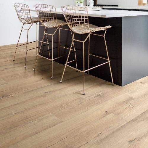 A kitchen with a wooden floor and three bar stools.