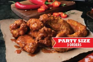 A bunch of chicken wings are sitting on a piece of paper on a table.