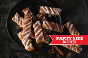 A plate of cinnamon sticks with icing and cinnamon sticks on a table.