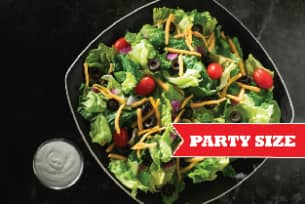 A salad in a bowl with a sign that says party size.